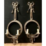 A pair of bronze neoclassical style wall sconces, vacant circular cartouche apertures, ribbon tied