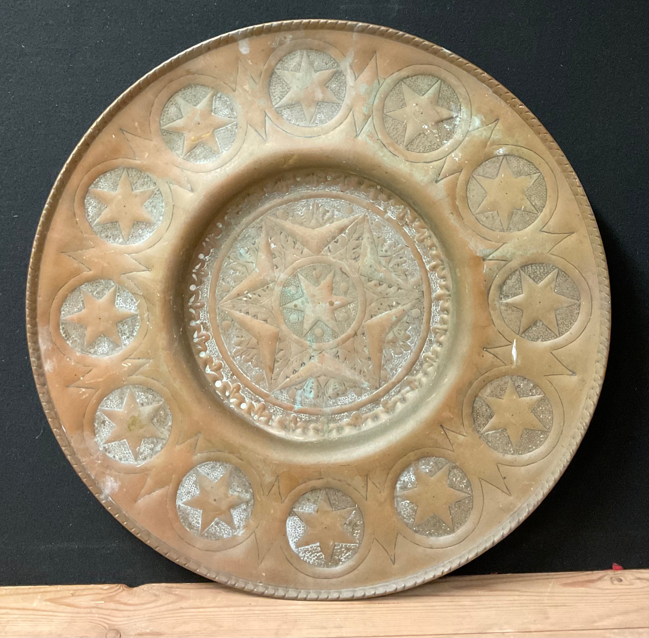 A large Middle Eastern brass charger or alms dish, chases with stars, 66.5cm diam, early 20th