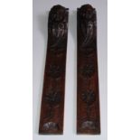 A pair of 19th century oak pilasters, carved with masks above stylised flowerheads, 46cm long