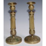 A pair of French Empre brass candlesticks, engine turned campana sconces and socles, fluted pillars,