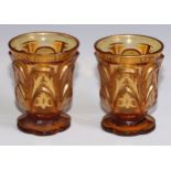 A pair of Bohemian amber glass beakers, moulded in the Gothic taste and picked out in gilt, 11.5cm