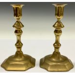 A pair of George II brass candlesticks, of seamed construction, knopped pillars, incurved domed