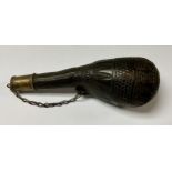 A late 19th/early 20th century Arabic leather shot or powder flask, formed from a dude, embossed and