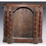 A 17th century Continental walnut sculpture niche or shrine, oversailing top above an arched frieze,