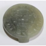 A Chinese jade circular buckle, carved with a dragon mask, 5.5cm diam