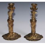 A pair of 19th century gilt bronze candlesticks, boldly cast with snakes coiled around lotus, Rococo