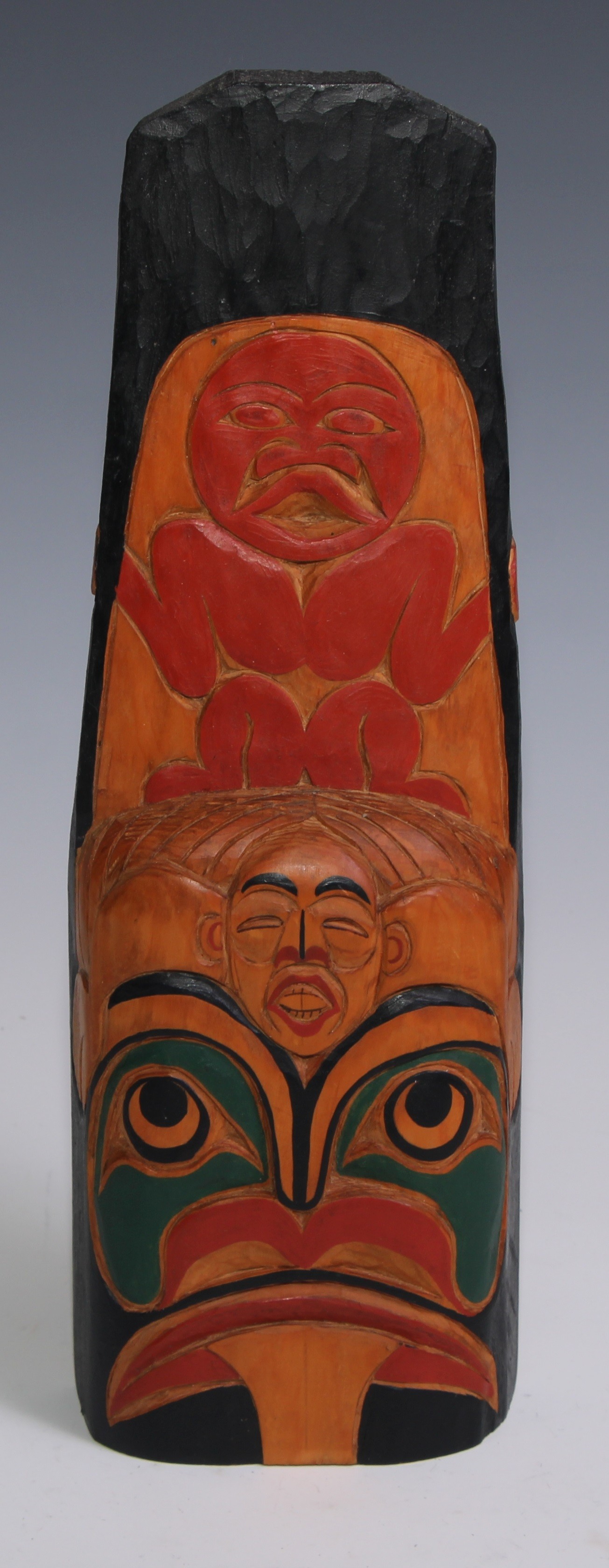 A Native American totem, carved and boldly painted in polychrome with stylised figures and features,