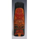 A Native American totem, carved and boldly painted in polychrome with stylised figures and features,