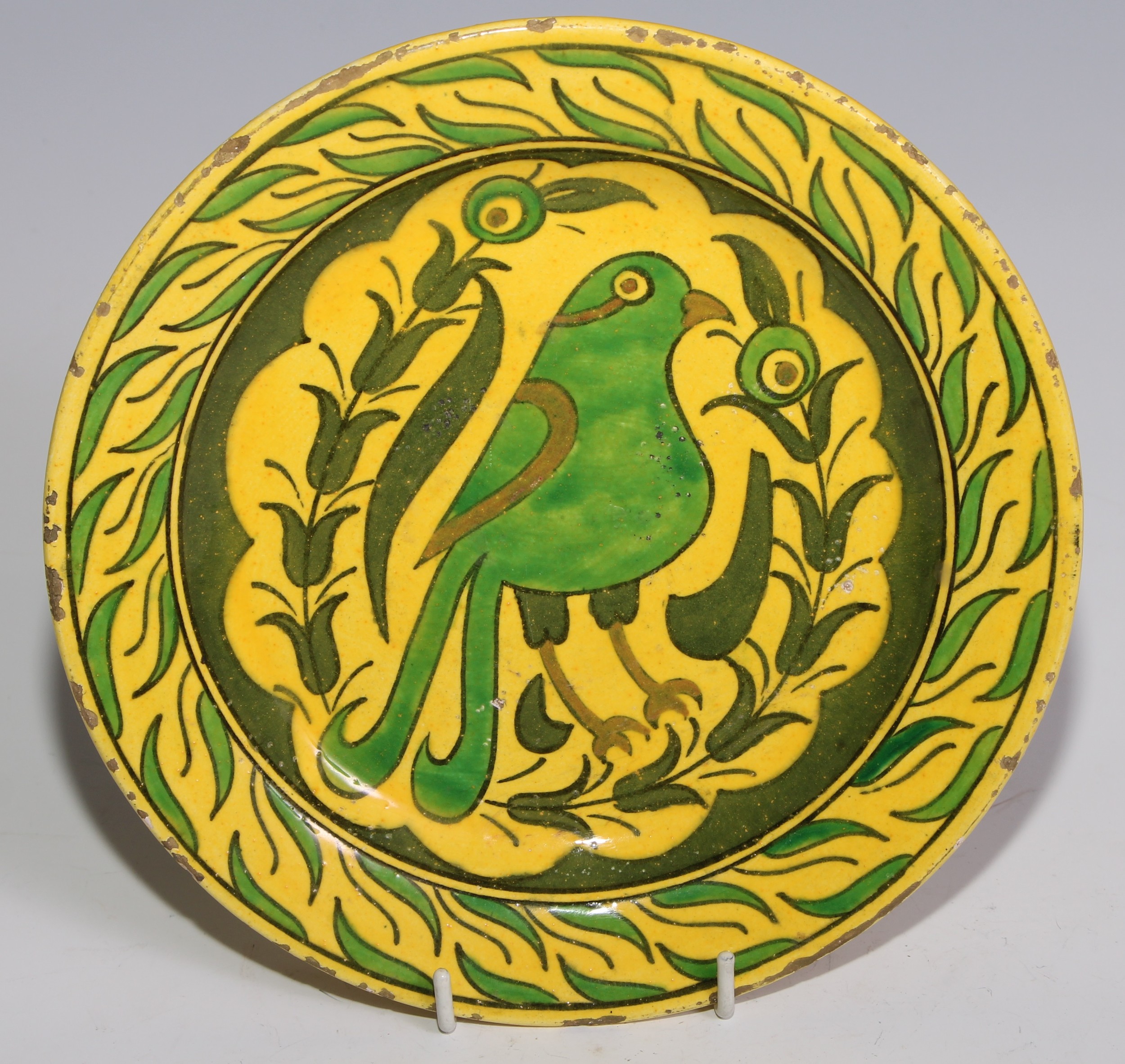 A Middle Eastern earthenware plate, painted in the Islamic taste with a bird, in tones of green