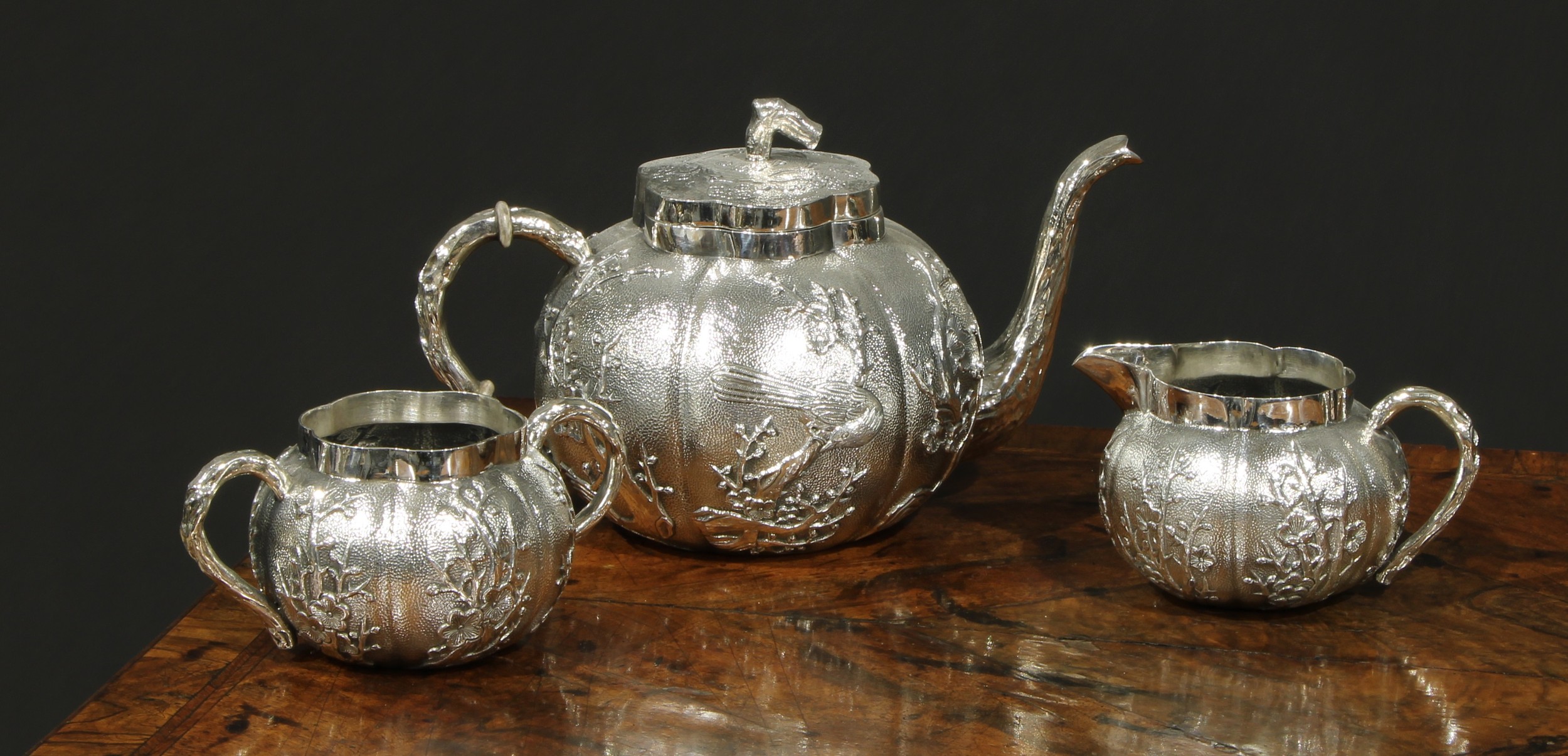 A Chinese silver three piece melon shaped tea service, comprising teapot, milk jug and sucrier,