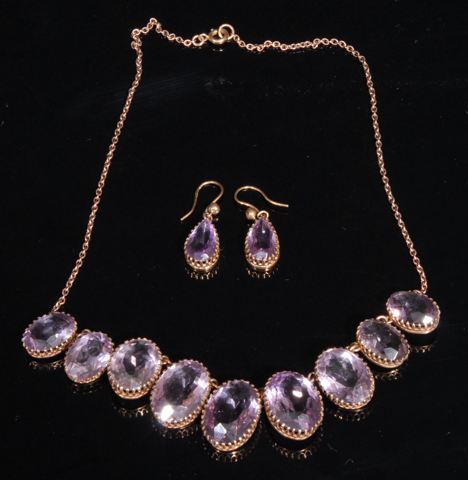 A 9ct rose gold and amethyst necklace and earring suite, the necklace set with nine graduated oval