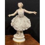 A German Volkstedt porcelain figure of a ballerina, wearing a lace porcelain skirt encrusted with