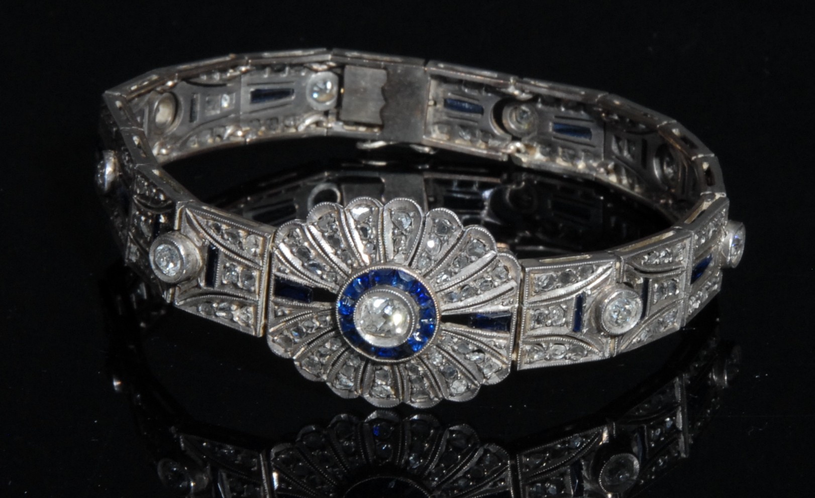 An Art Deco diamond and sapphire panel bracelet in the manner of Cartier, each panel centered with