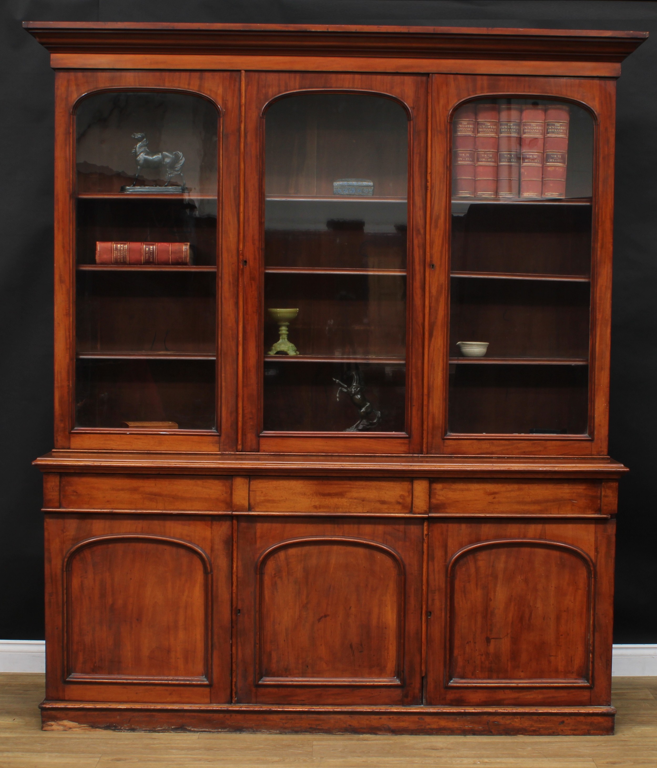 A Victorian mahogany library bookcase, moulded cornice above three glazed doors enclosing adjustable