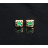 A pair of rectangular emerald solitaire ear studs, the cushion cut stone claw set within open work