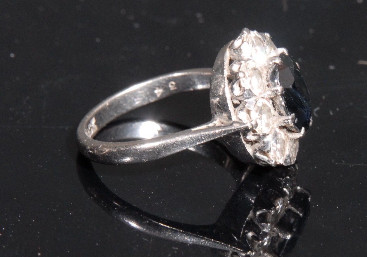 An 18ct white gold sapphire and diamond flowerhead cluster ring, the central oval cut sapphire 8mm x - Image 2 of 2