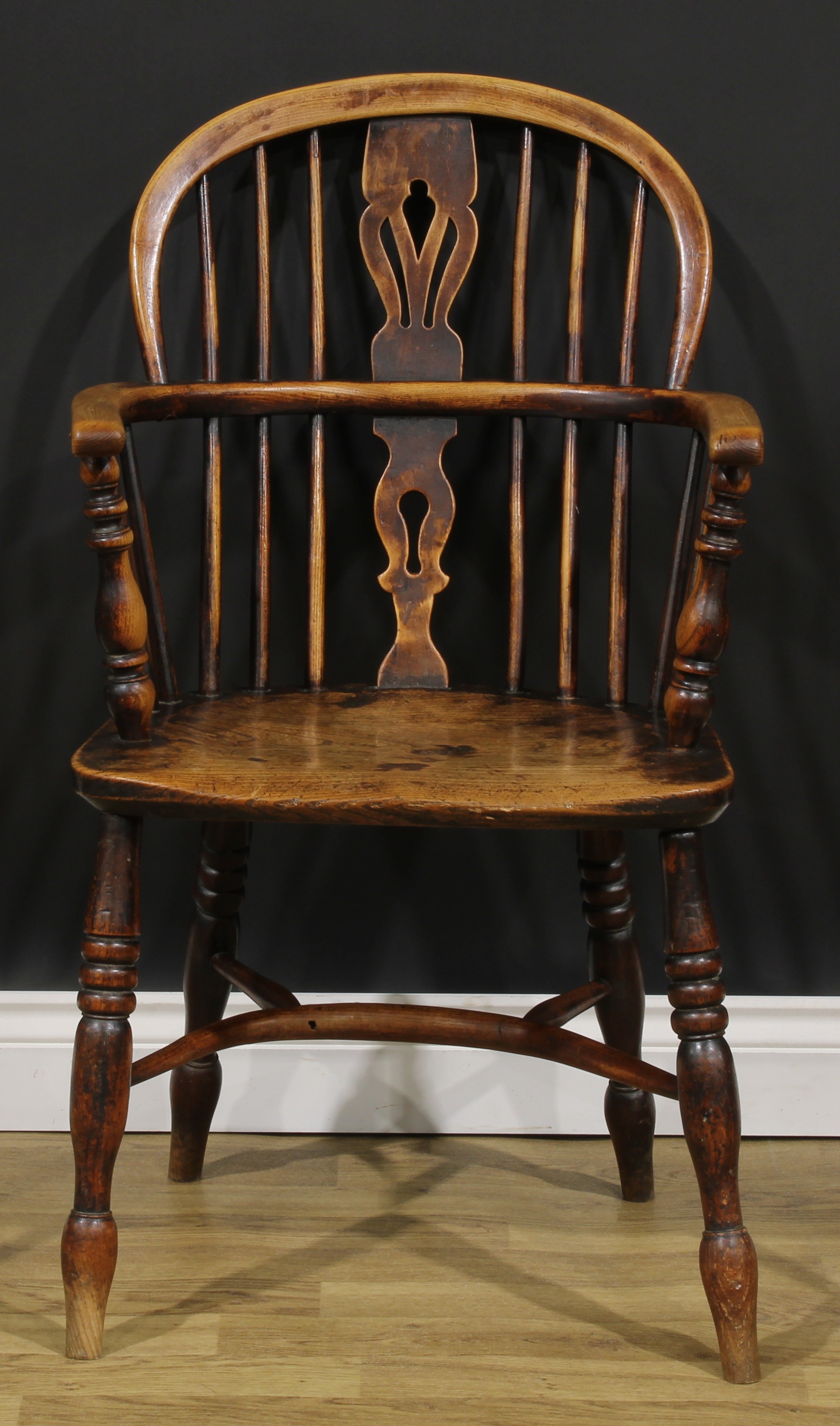 A 19th century East Midlands ash and elm Windsor elbow chair, low hoop back, shaped and pierced