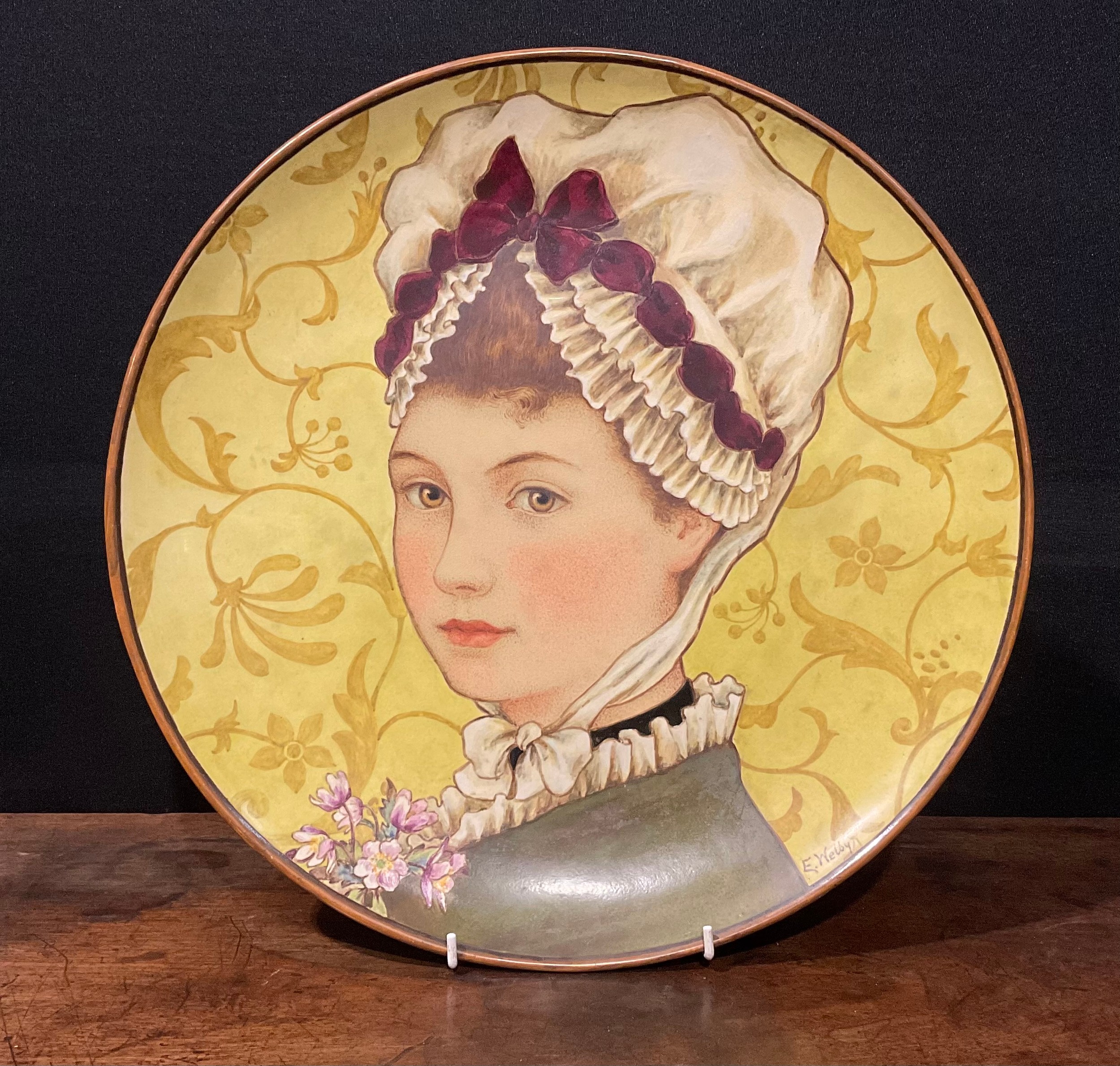 A Minton Aesthetic Movement circular charger, painted by E Welby, with a portrait of a Victorian