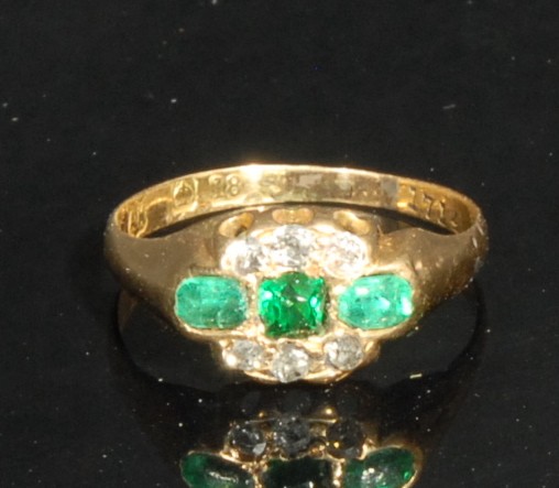 An 18ct gold 18th century style ring, set with three emeralds, flanked by six old cut diamond chips,