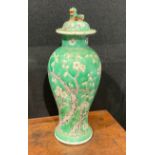A Chinese baluster vase and cover, painted with blossoming prunus on a green ground, Dog of Fo