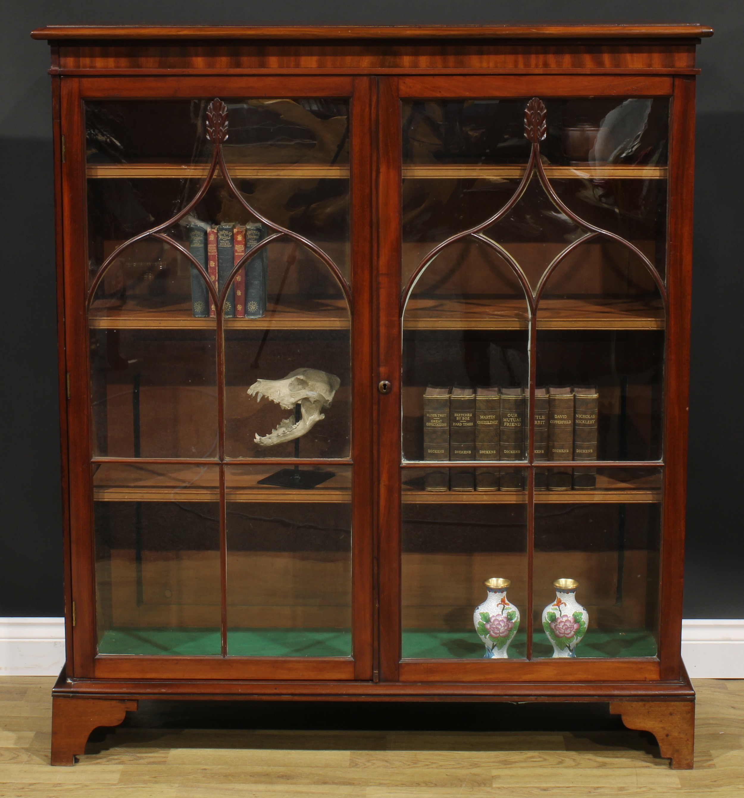 A 19th century mahogany low library bookcase, oversailing top above a pair of glazed doors enclosing