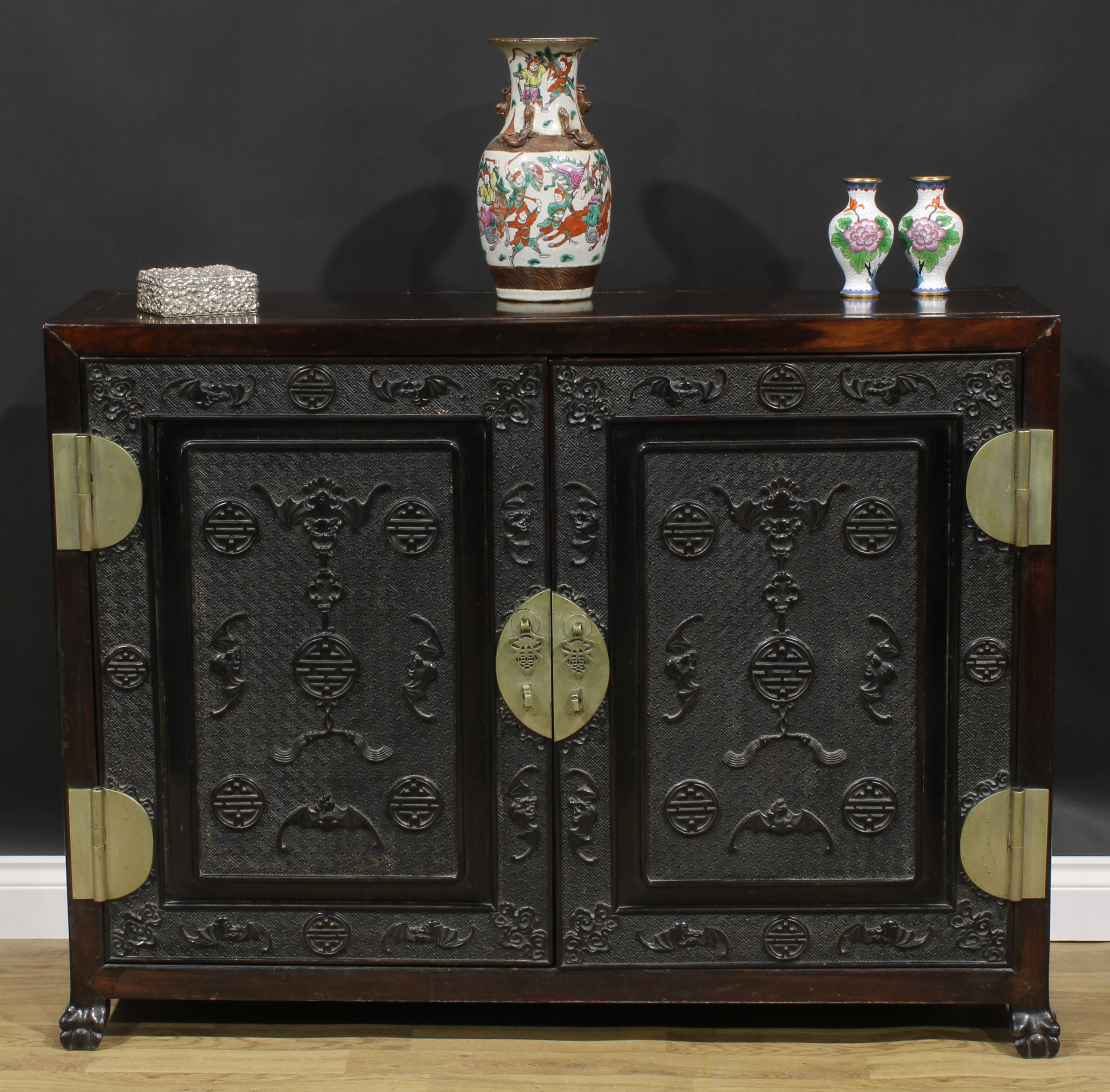 A Chinese hardwood side cabinet, rectangular top above a pair of panel doors carved and applied with