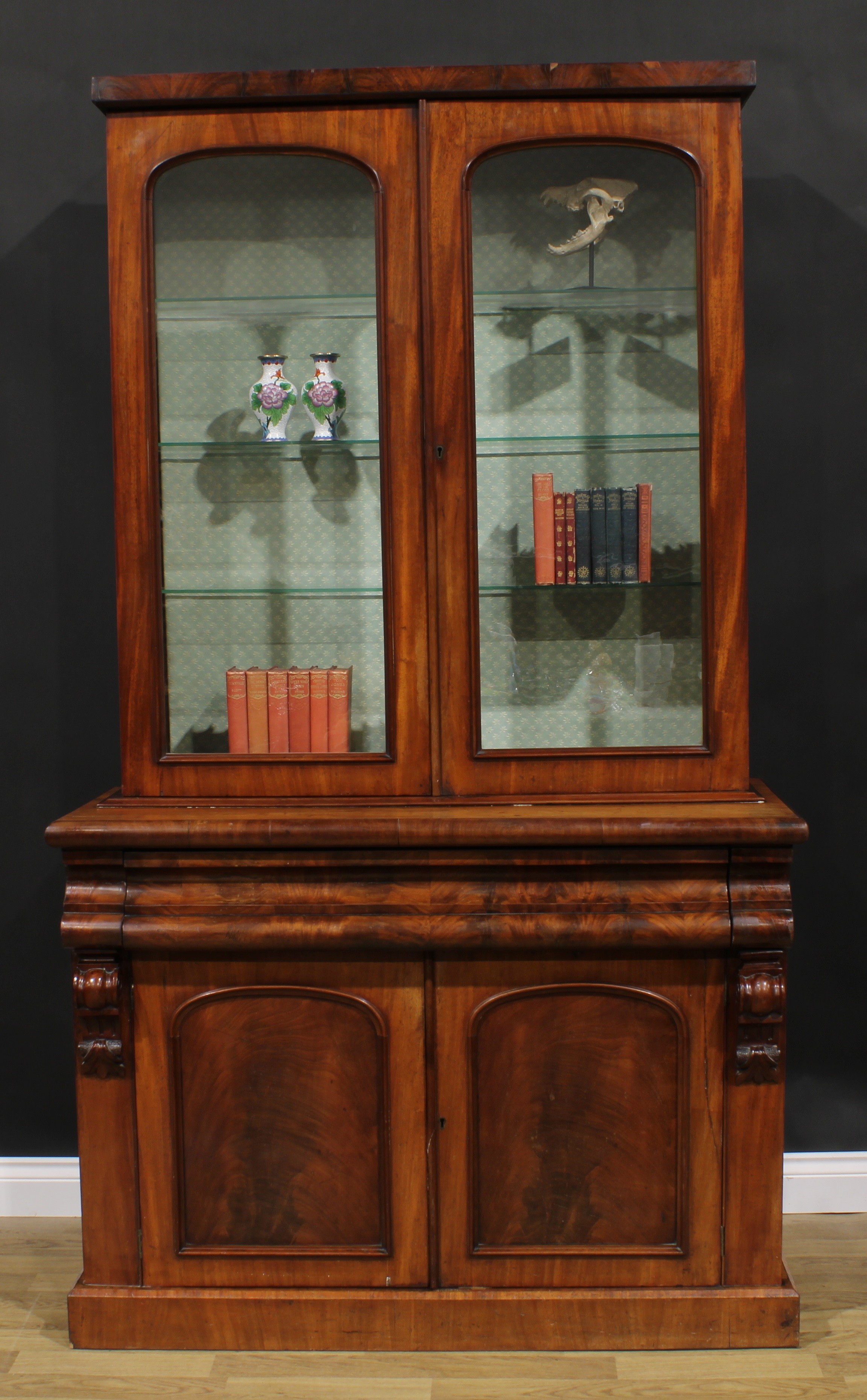 A Victorian mahogany library bookcase, rectangular cornice above a pair of arched glazed doors,