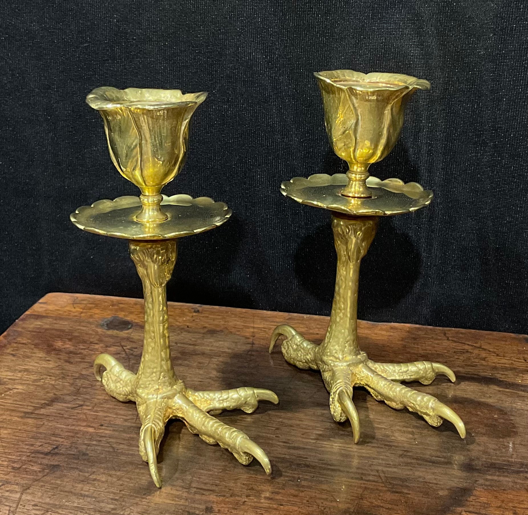 A pair of brass candlesticks, each base cast as an eagles foot, foliate moulded nozzles, shaped