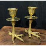 A pair of brass candlesticks, each base cast as an eagles foot, foliate moulded nozzles, shaped