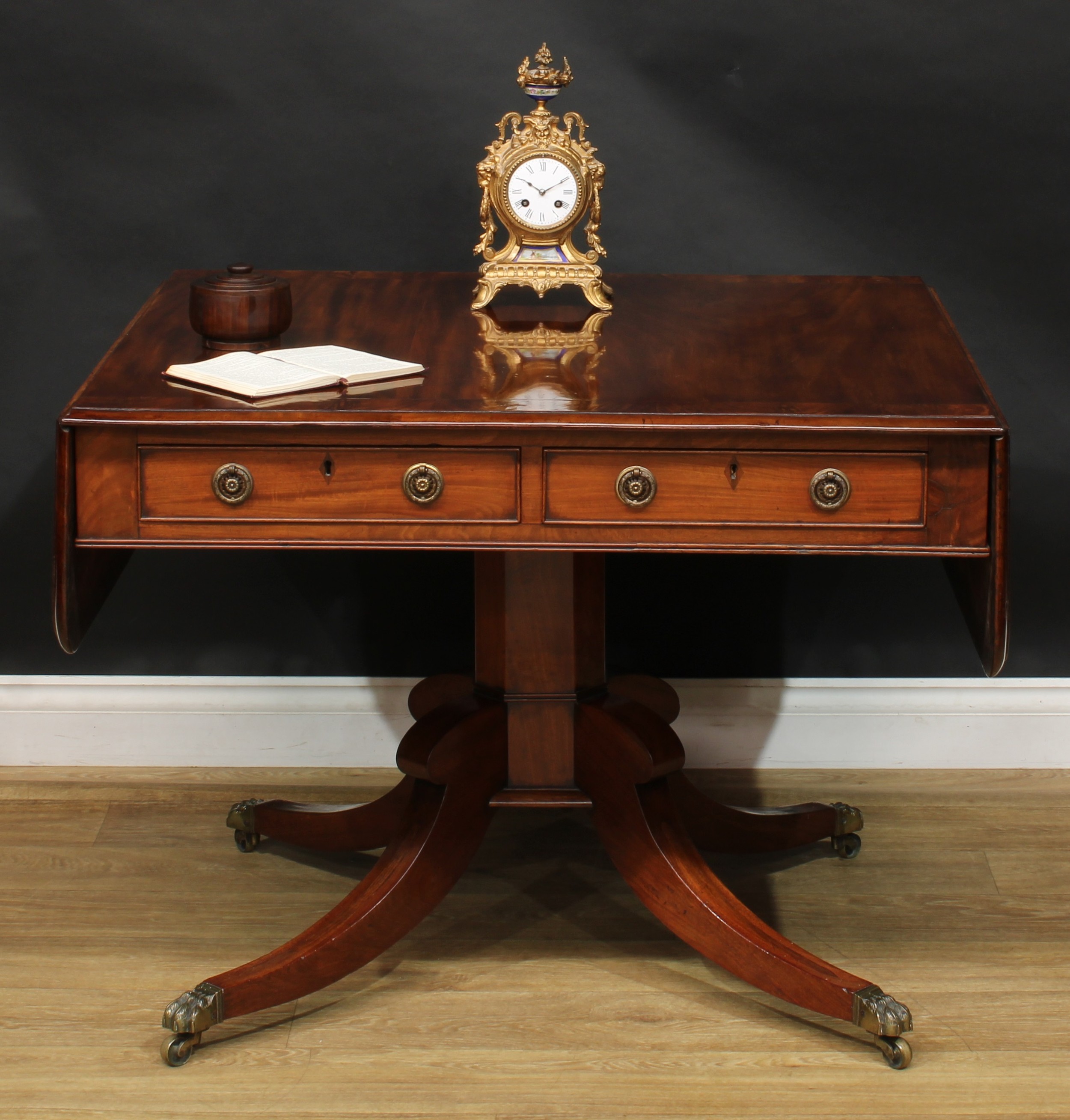 A Regency flame crossbanded mahogany sofa table, rounded rectangular top with fall leaves above a