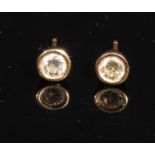 A pair of round brilliant cut diamond ear studs, bezel set, each diamond approximately 0.2-0.25ct