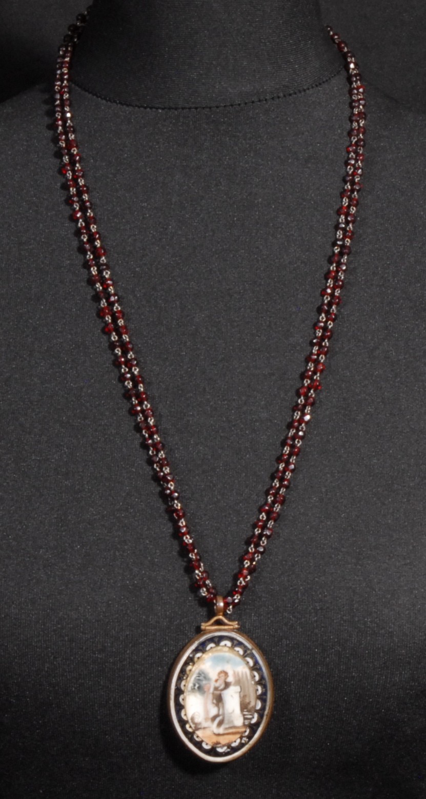 A late 18th/early 19th century mourning pendant, with blonde waxed hair, garnet rosary bead necklace