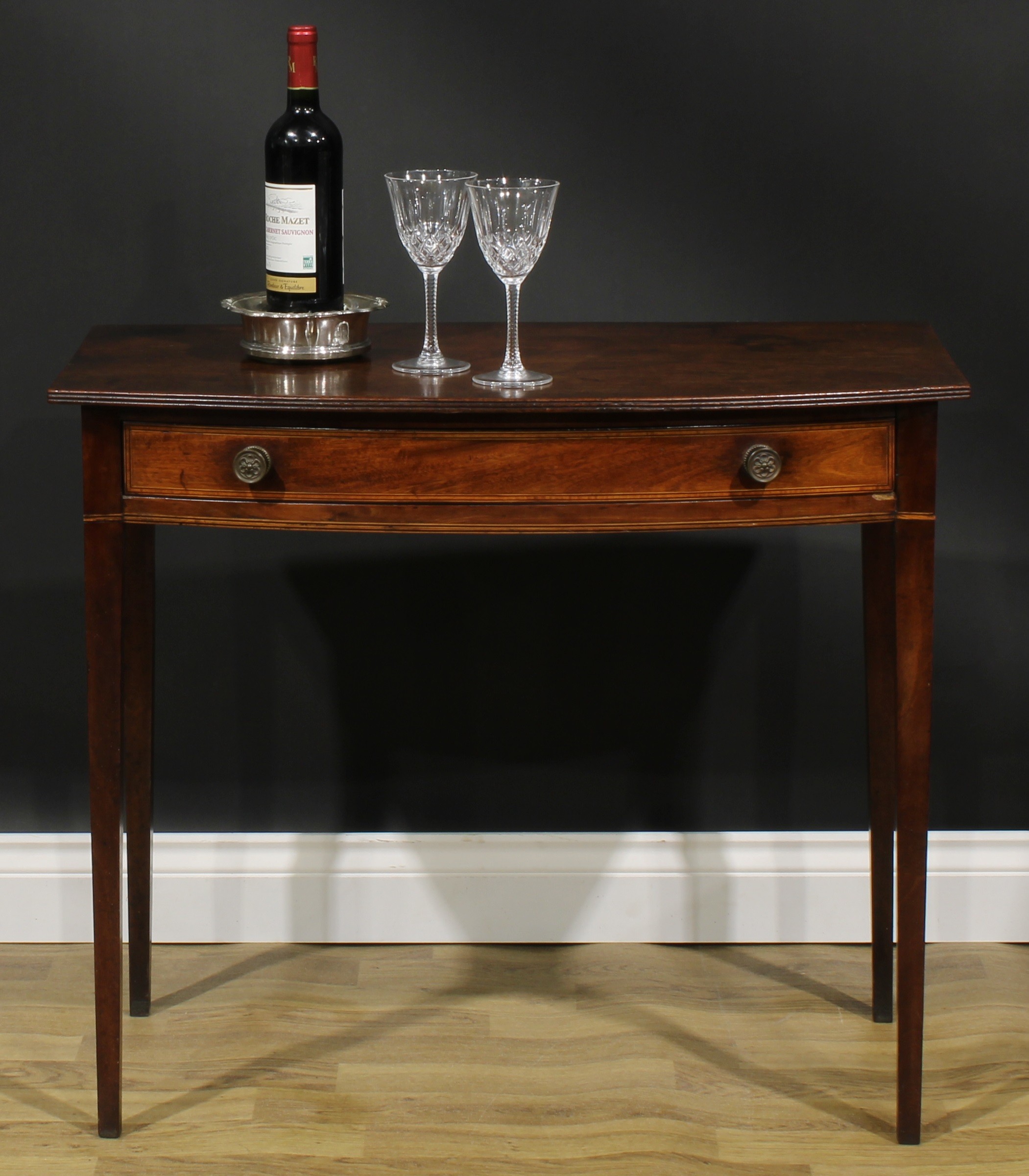 A George III mahogany bowfront side table, oversailing top with reeded edge above a long satinwood