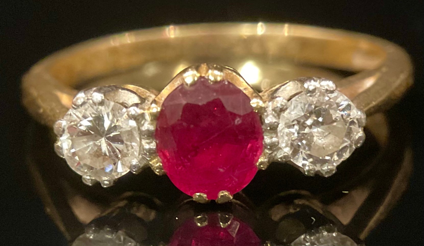 A diamond, rub and 18ct gold three stone ring, the central ruby flanked by a pair of round brilliant