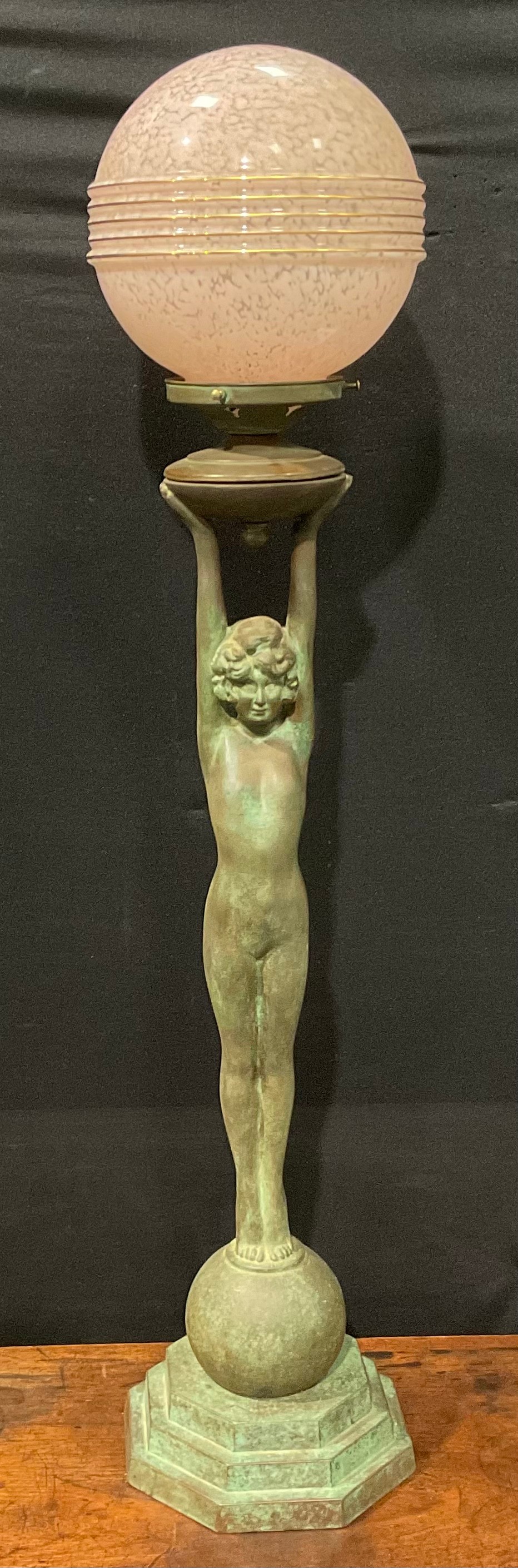 An Art Deco style copper figural table lamp, as a female nude, glass globular shade, stepped