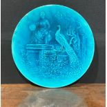 A Burmantofts Faience circular wall plaque, decorated in low relief with peacocks in stately garden,