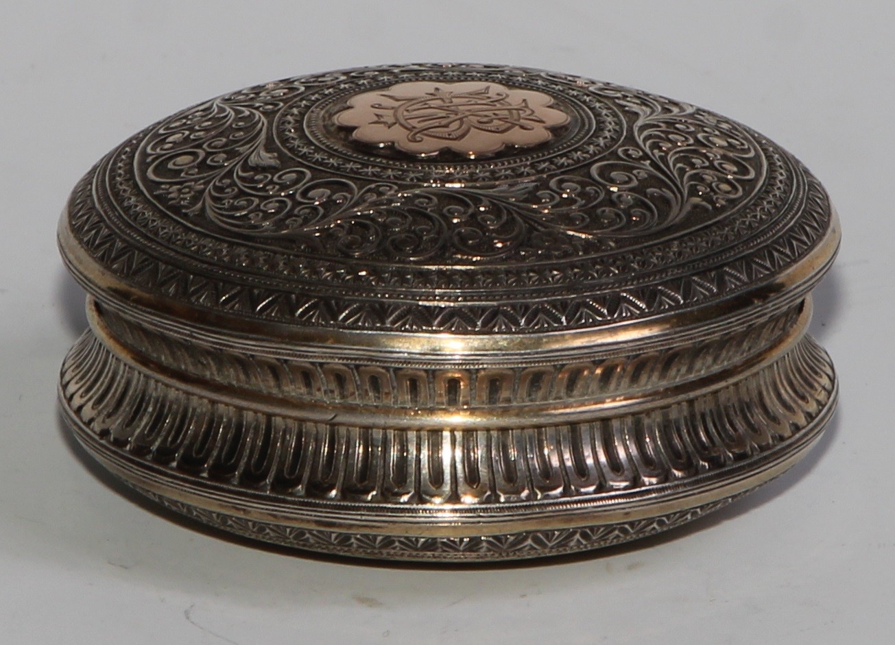 A 19th century silver and gold coloured metal circular snuff box, chased overall in the Indian - Image 2 of 5