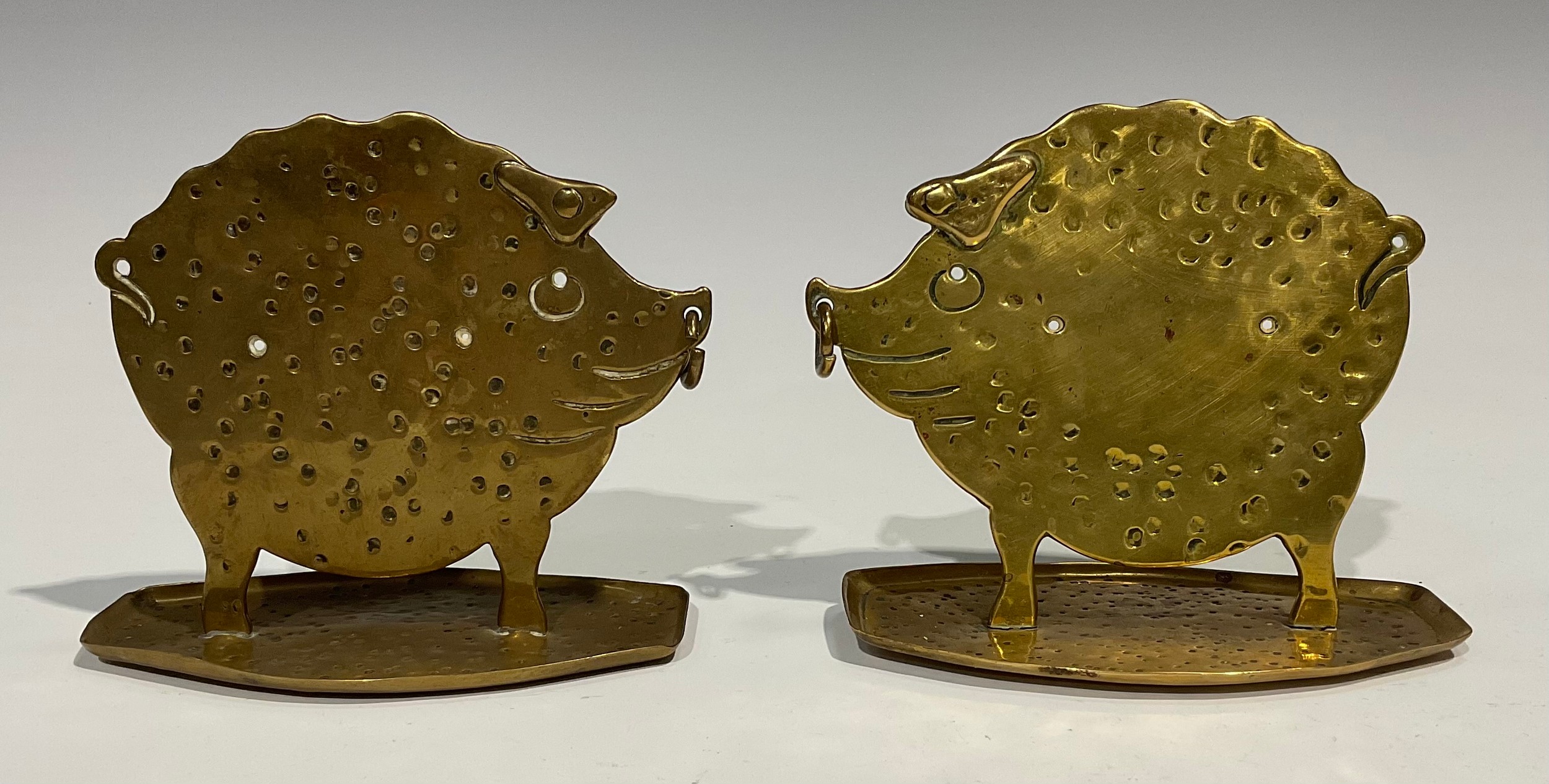 A pair of German Arts and Crafts brass models, of stylised pigs, in silhouette, planished overall,