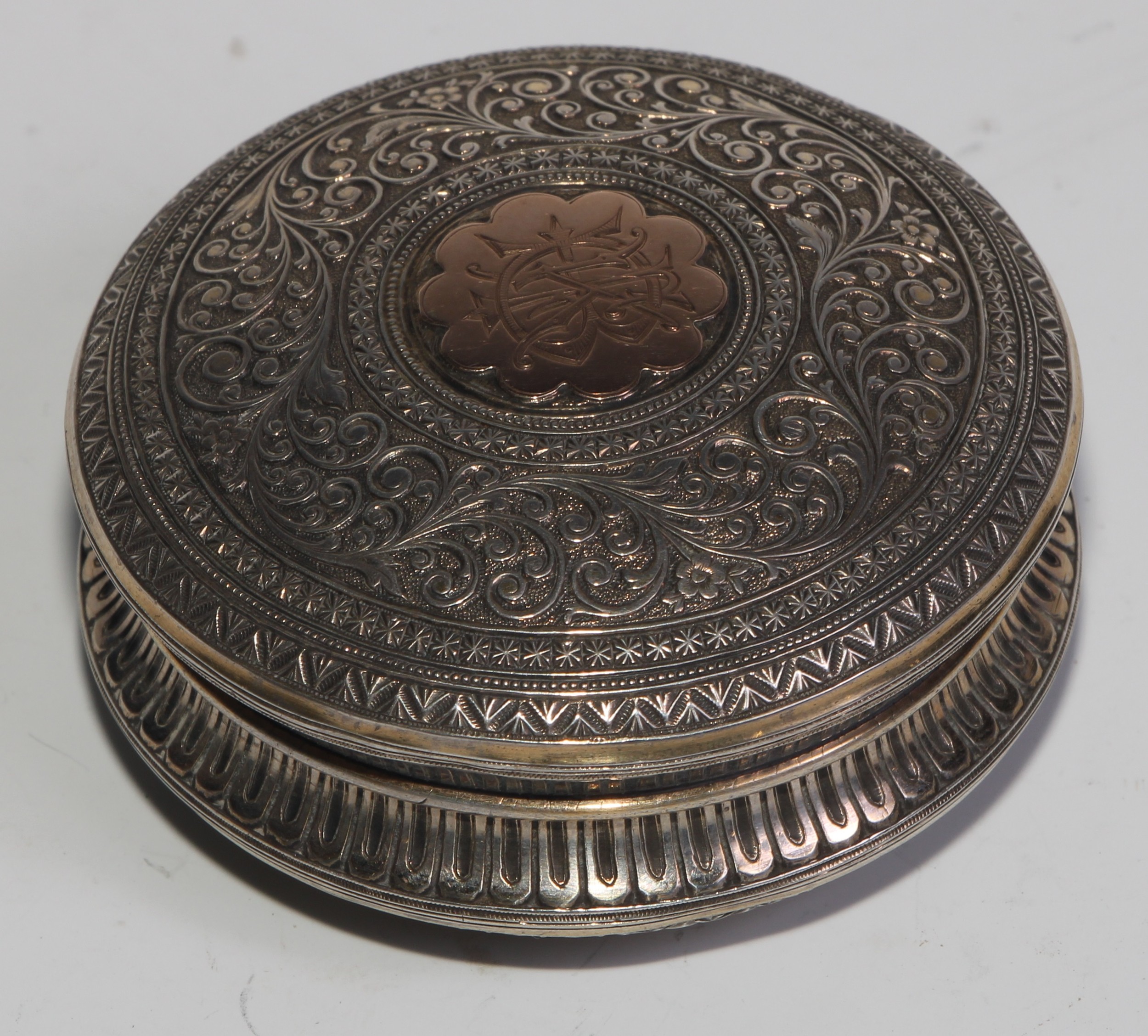 A 19th century silver and gold coloured metal circular snuff box, chased overall in the Indian - Image 3 of 5