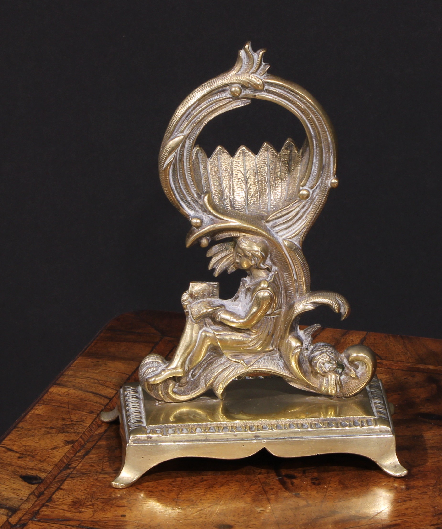 A 19th century brass pocket watch stand, cast in the Rococo taste with a figure reading, 17cm