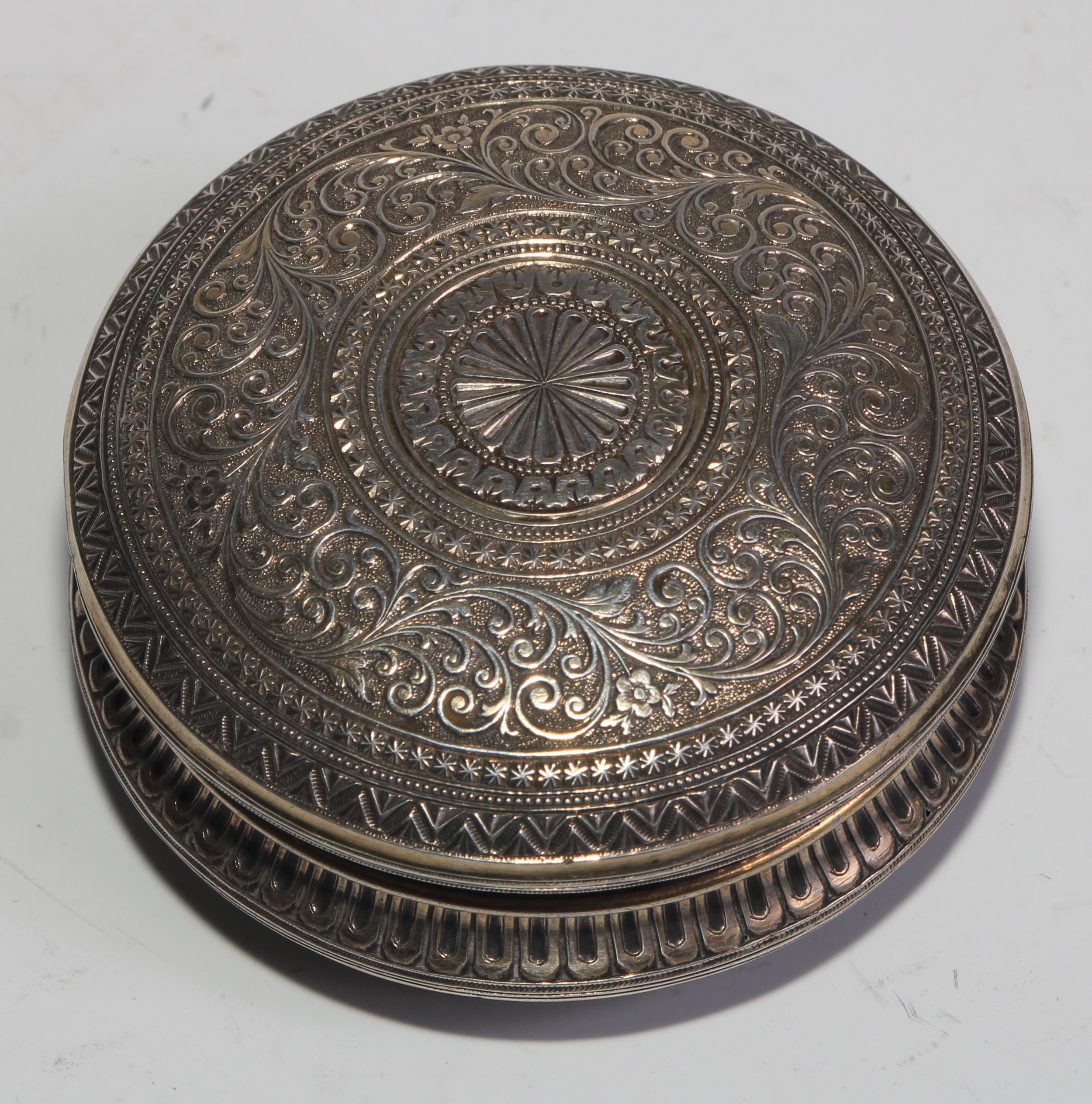 A 19th century silver and gold coloured metal circular snuff box, chased overall in the Indian - Image 5 of 5