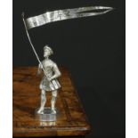 A Continental silver figure, of a Renaissance soldier holding a pennant, he stands, upon a barrel