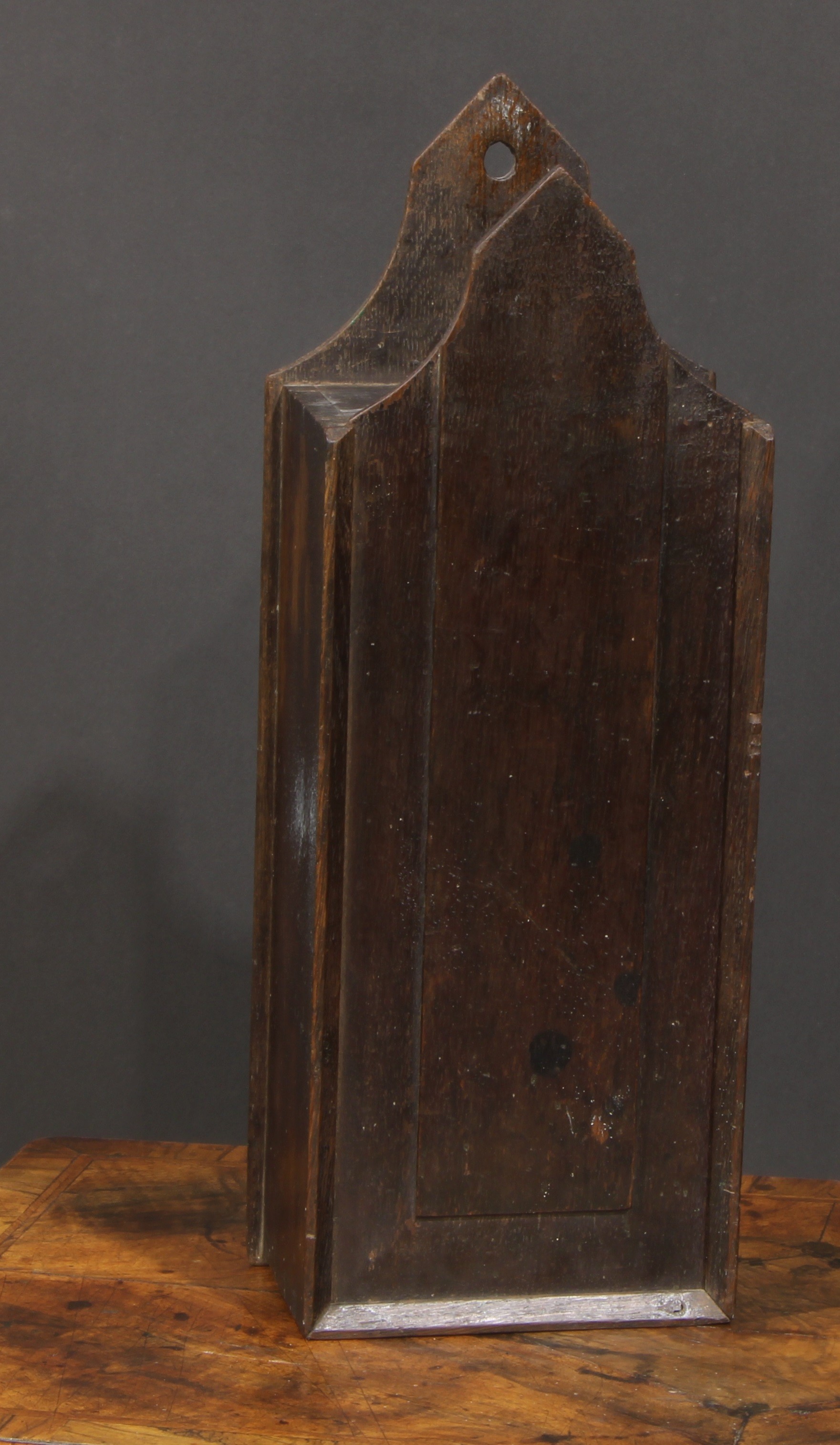 A George III oak candle box, possibly Welsh, pointed arched cresting, raised panelled sliding cover,