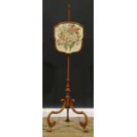 A 19th century walnut pole screen, shield shaped banner with silk panel embroidered with a spray