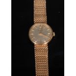 A 9ct gold ladies Omega wristwatch, the 2cm circular champagne dial with baton numeral markers, mesh