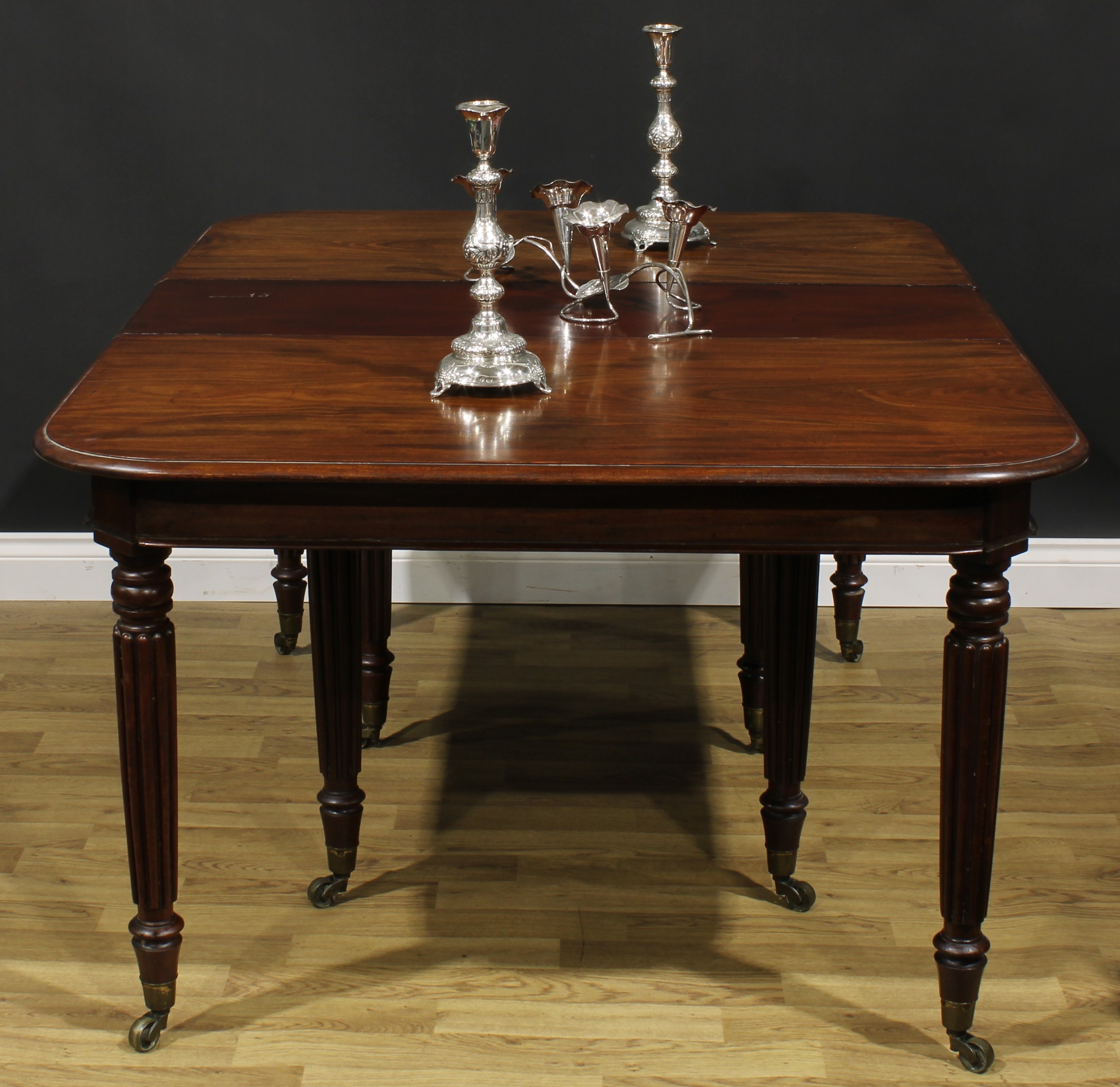 A George/William IV mahogany extending dining table, rounded rectangular top with two