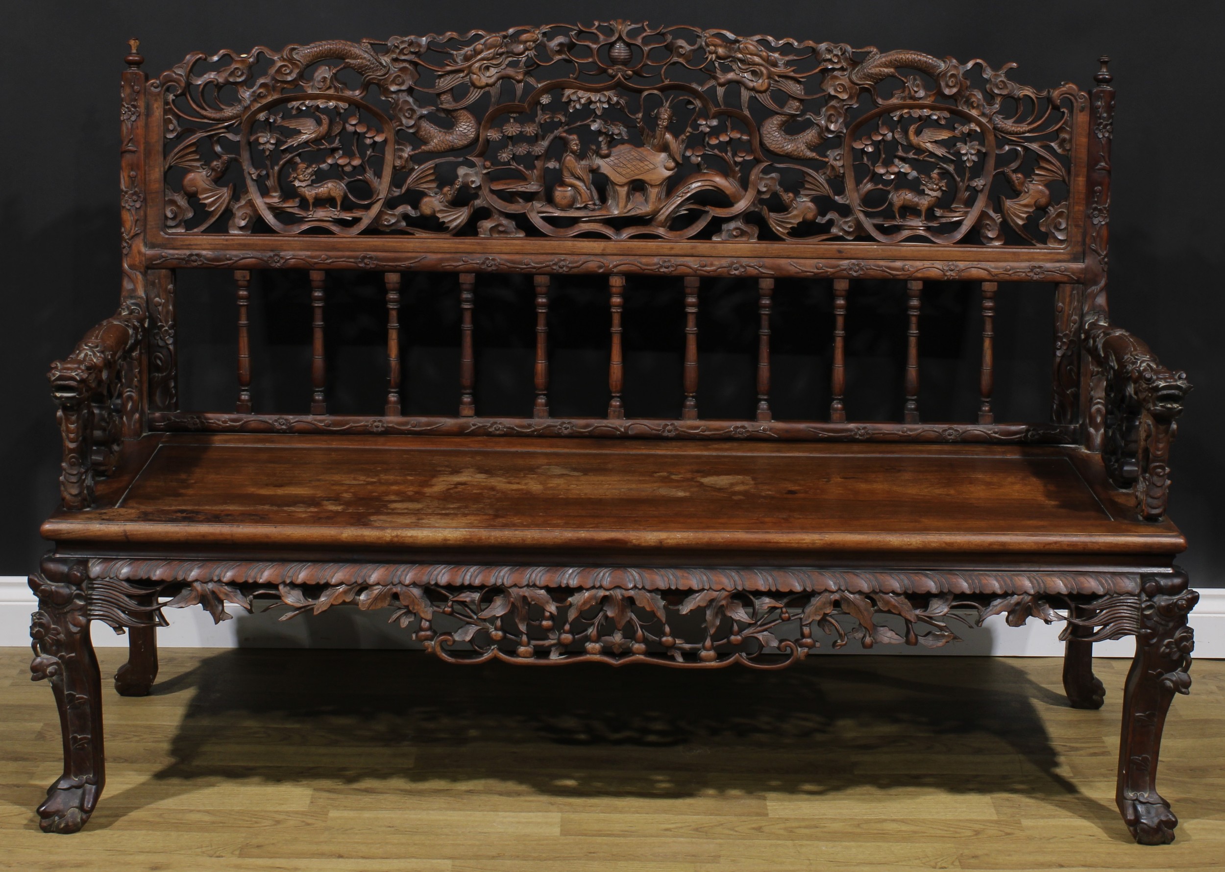 A Chinese hardwood bench or settle, arched cresting pierced and profusely carved with dragons,