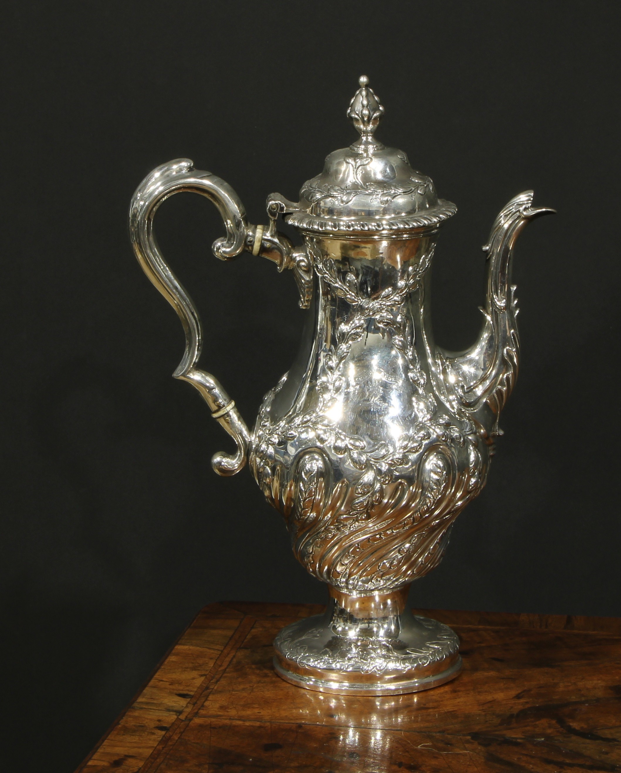 An early George III silver baluster coffee pot, wrythen half-fluted and chased with leafy