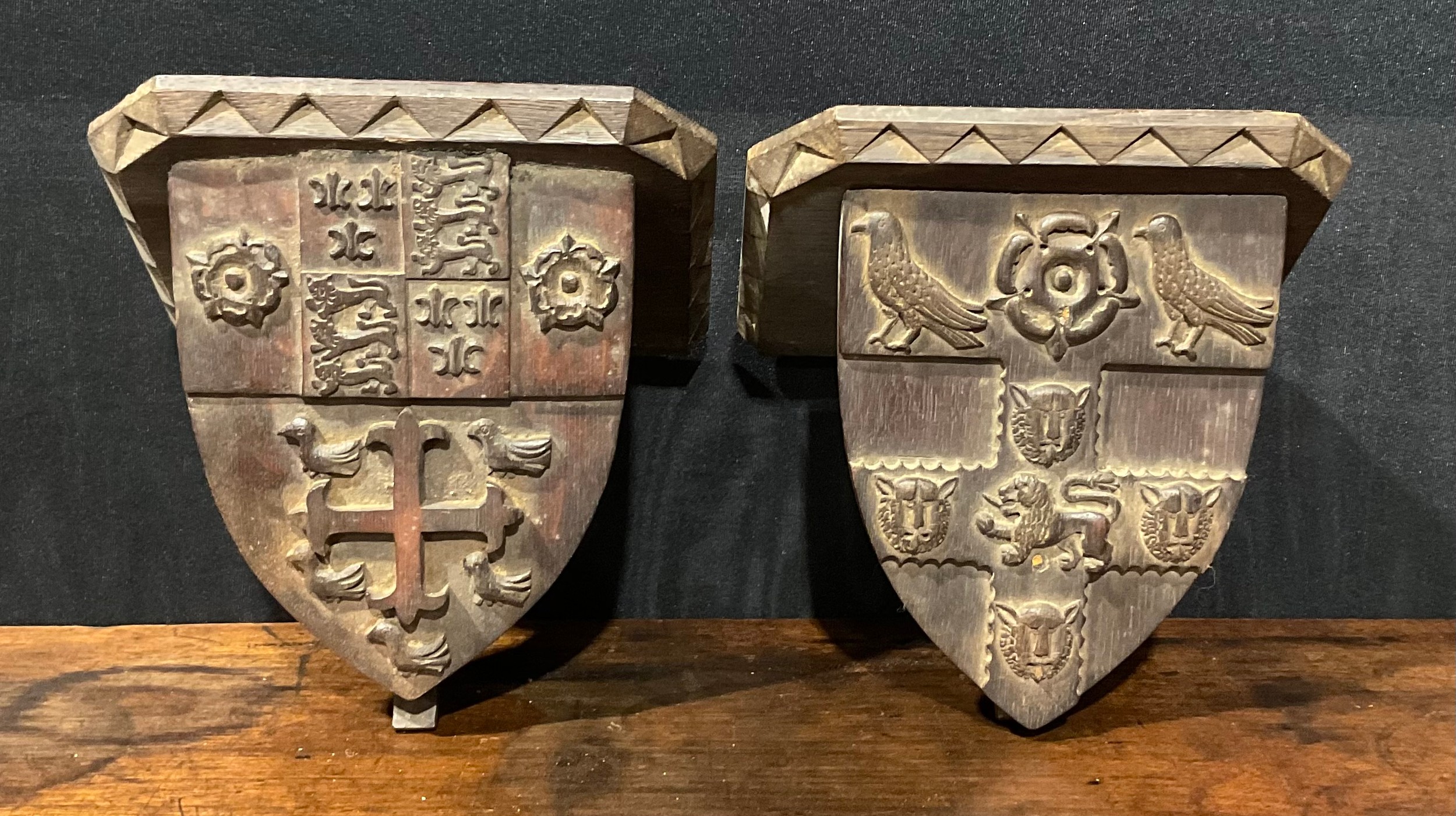 A pair of 19th century Gothic Revival oak armorial wall brackets, carved with the coats of arms of