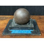 A 19th century cast iron cannonball, the collector’s stand with label inscribed Russian round shot